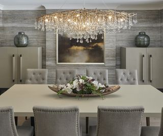 dining furniture with huge chandelier above and metallic wallpaper