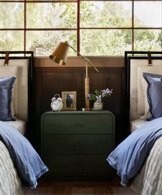 A bedroom with two twin beds and a green side table in the middle.