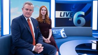 Hugh Bonneville (Douglas) and Karen Gillian (Madeline) pose on a TV news set in a promotional image for Douglas is Cancelled