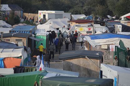 Migrants walk through the Jungle camp on Sunday.