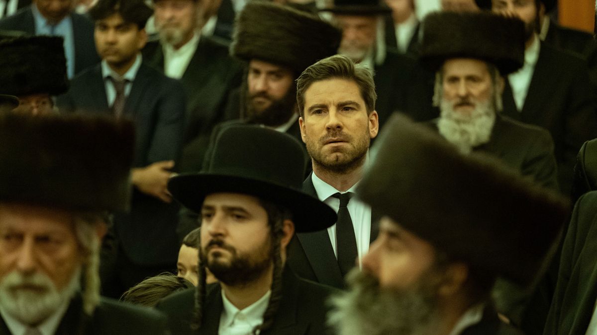 Noah (Kevin Jannsens) in a black suit in a crowd of men in Rough diamonds