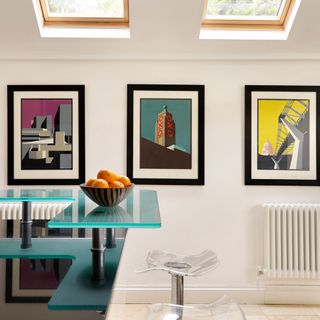 kitchen area with frames on wall and glass table with glass chairs
