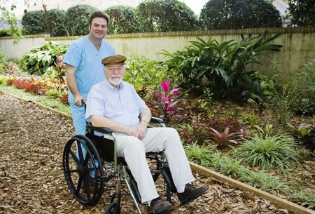 Man In Scrubs Pushing Elderly Man In A Garden