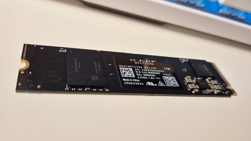 Photo of a black SSD sitting on a white gaming desk with a keyboard in the background.