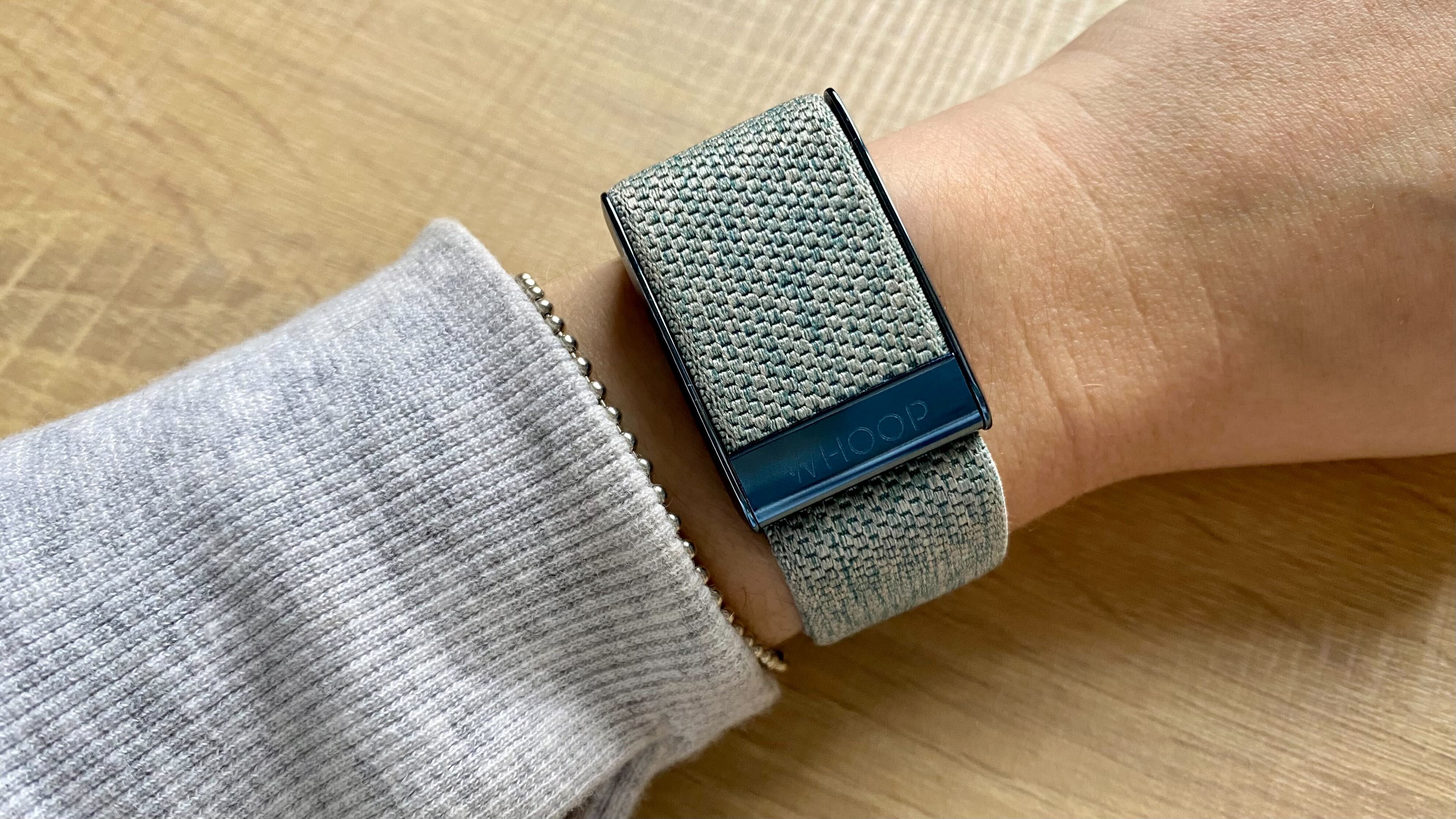 A photo of the Whoop with a blue wristband on the wrist