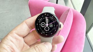 Google Pixel Watch 3 in a user's hand against a pink background