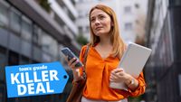 Woman in orange top using a mobile phone and holding a laptop with 'Killer Deal' badge overlaid