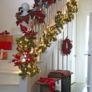 With staircase in hallway with Christmas decorations and lights.