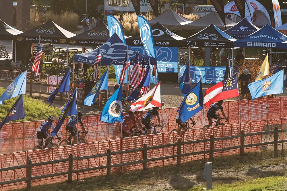 The lead group of riders as they pass through a corridor of flags after the finish stretch.