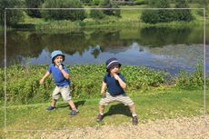 Two little boys crouching in front of a lake