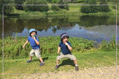 Two little boys crouching in front of a lake