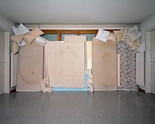 A wall with bedding and pillows covering it.