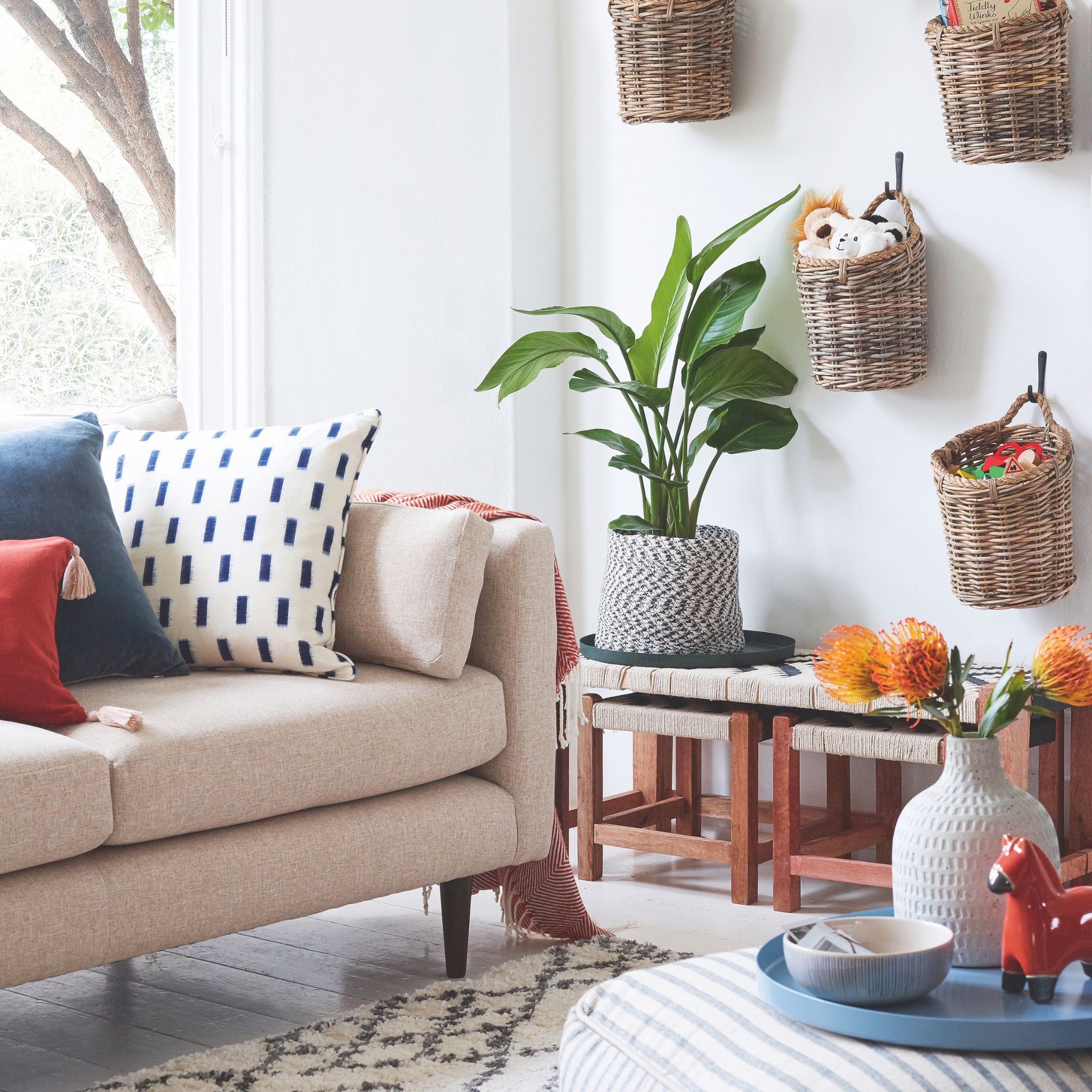 White painted living room with a beige sofa and woven storage baskets on the wall