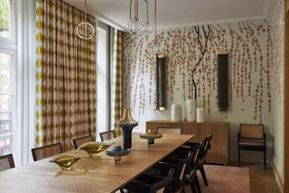 A dining room with a wooden table and a mural of a blossoming tree on the walls