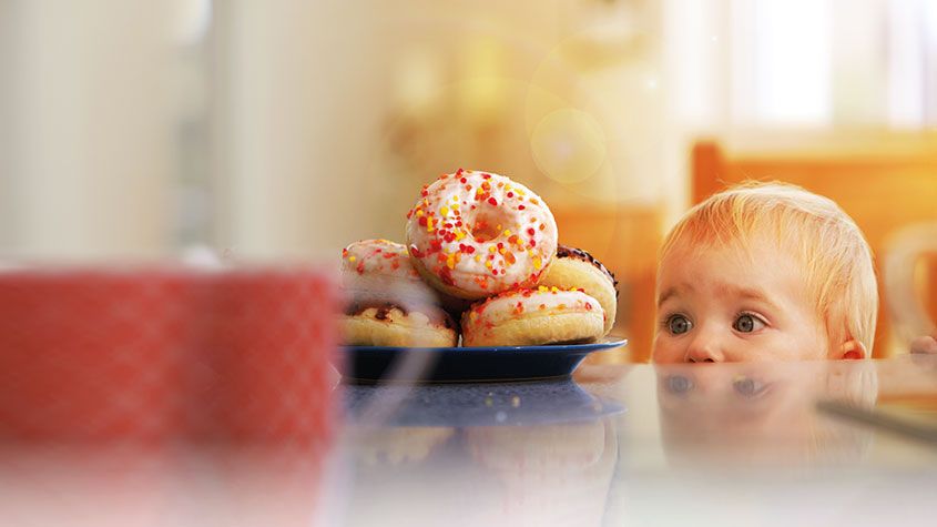 Small child staring at a pile of doughnuts