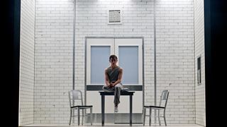 Henry Creel sits a lone on a table in a stale white room