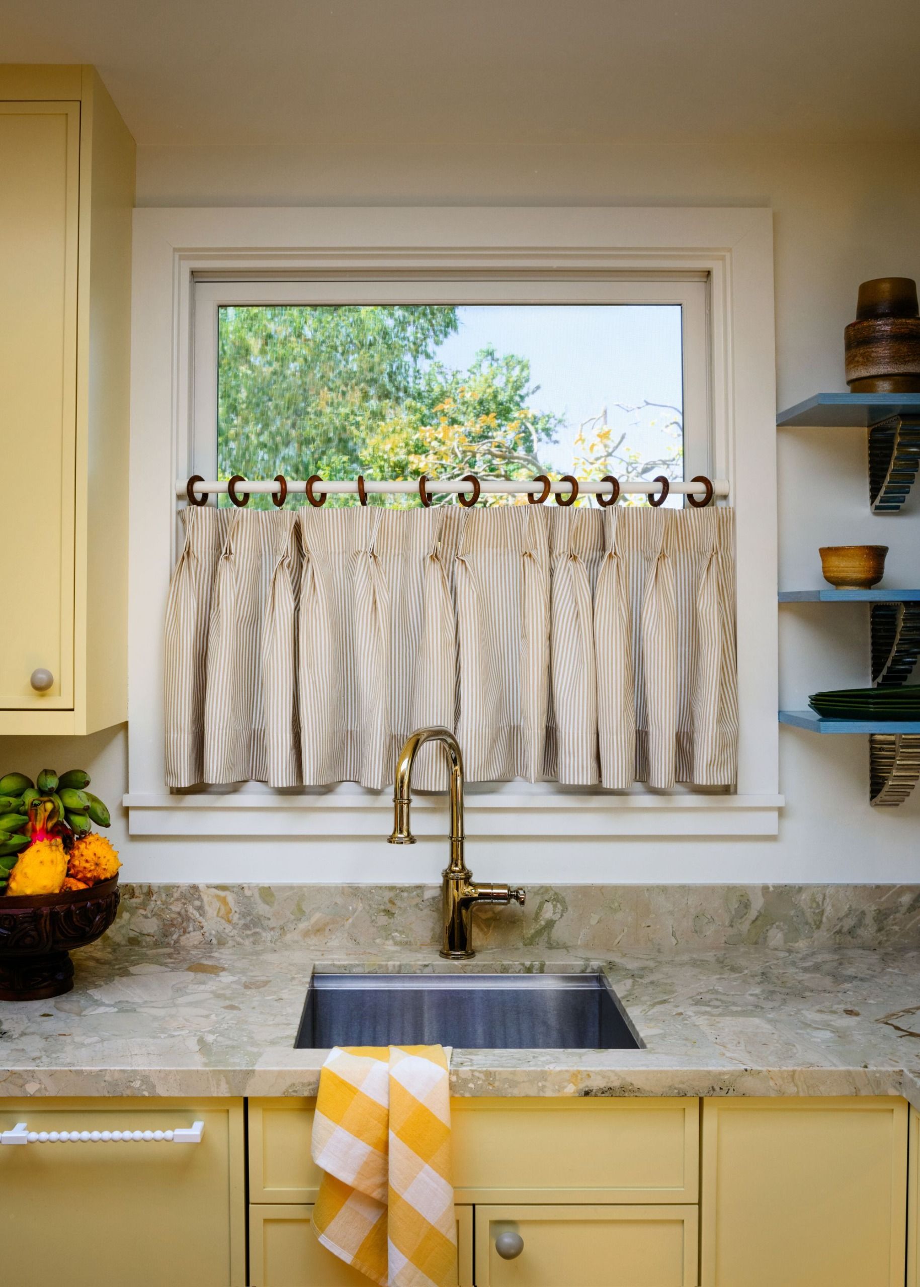 A kitchen with sunny yellow cabinets and island, tall bar stools and an organic countertop light 