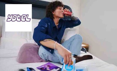 yotel logo top left with a woman sipping from a can in a hotel room 