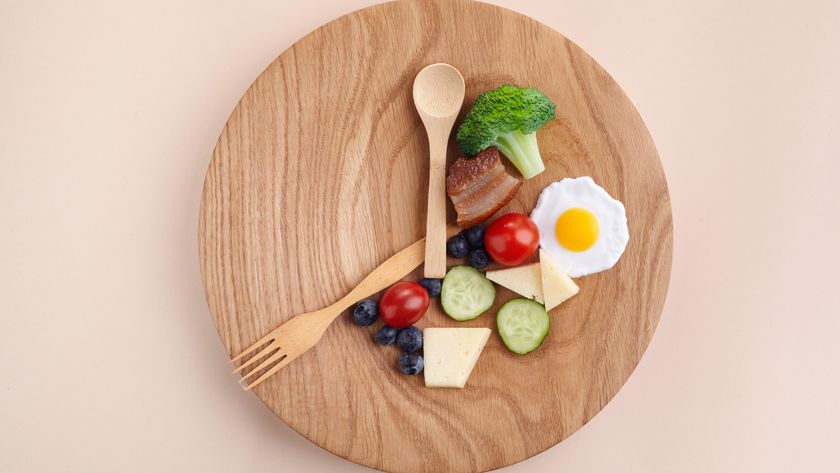 An artful amount of food placed on a wooden plate with wooden cutlery