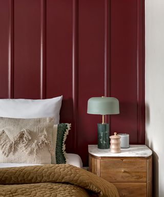 bedroom with burgundy panelled wall, wooden nightstand and cozy neutral bedding