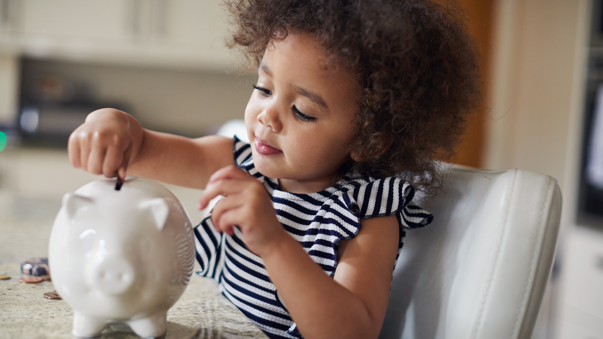 Little girl putting money into her piggy bank