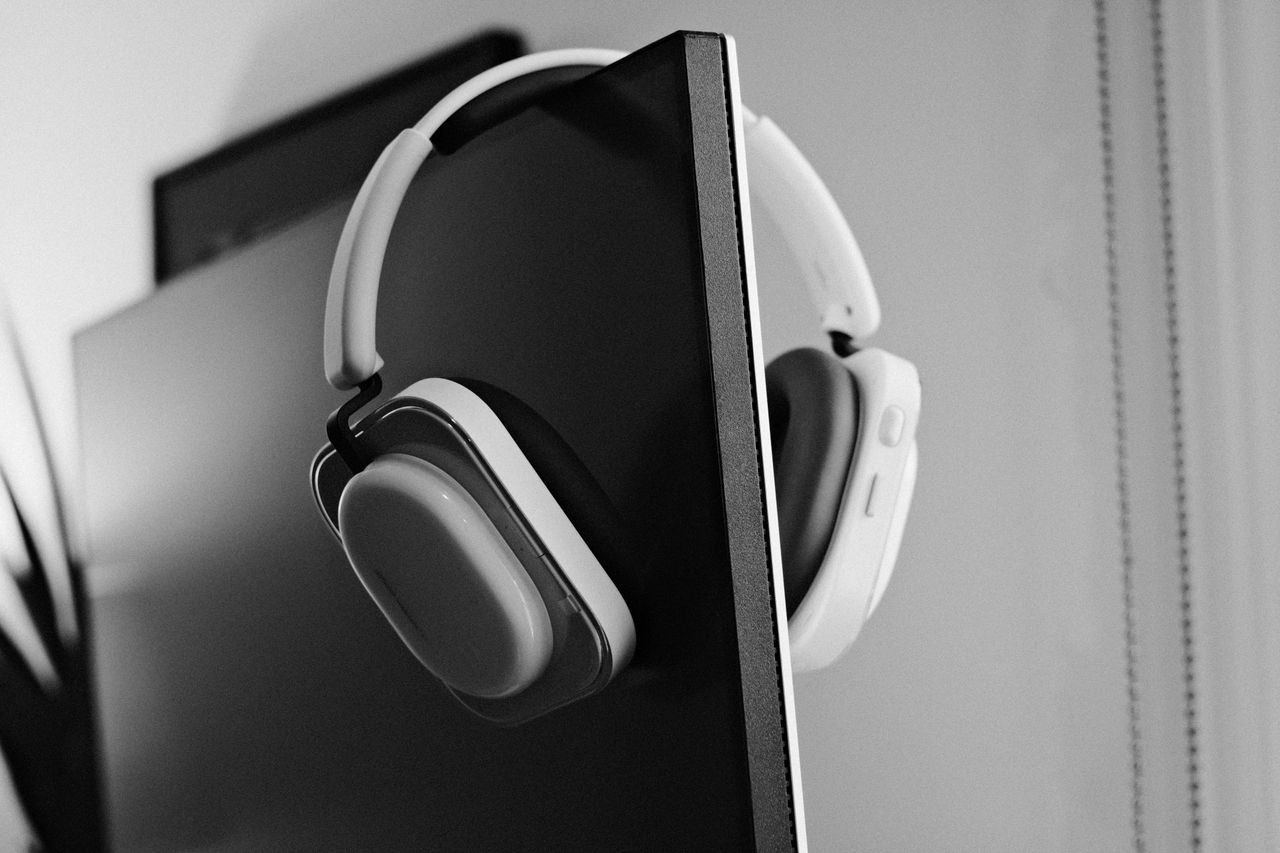 Black-and-white photo of headphones hanging over a computer monitor