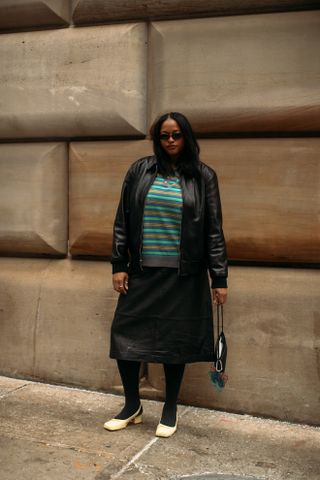 woman wearing striped shirt, leather jacket, skirt, and heels