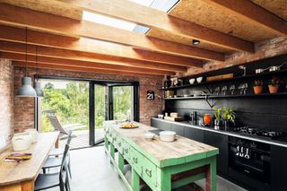 Black and green kitchen diner with OSB ceiling