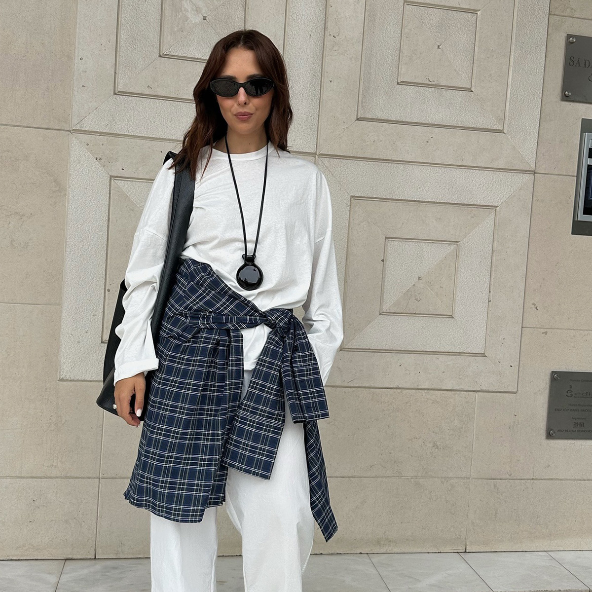 Debora Rosa wearing a white tee, white jeans, and a plaid shirt around her waist. 