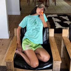 Influencer wearing green lace-trim satin shorts with a bright blue T-shirt and camo baseball cap