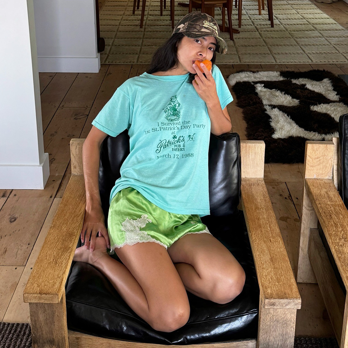 Influencer wearing green lace-trim satin shorts with a bright blue T-shirt and camo baseball cap