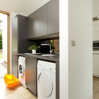 narrow utility room with sink washing machine and tumble dryer