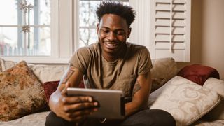 Man having video call on tablet while sitting on couch