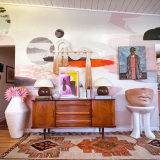 Sponge painted pink and neutral wall with wooden mid century modern chest and eclectic art, accessories combination