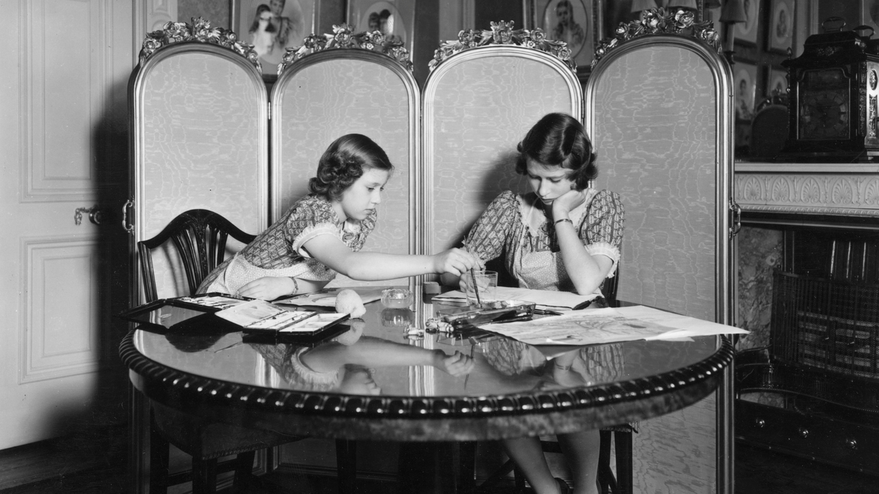 Princess Margaret Rose (1930 - 2002) and Princess Elizabeth (right) working on paintings in the school room of Buckingham Palace