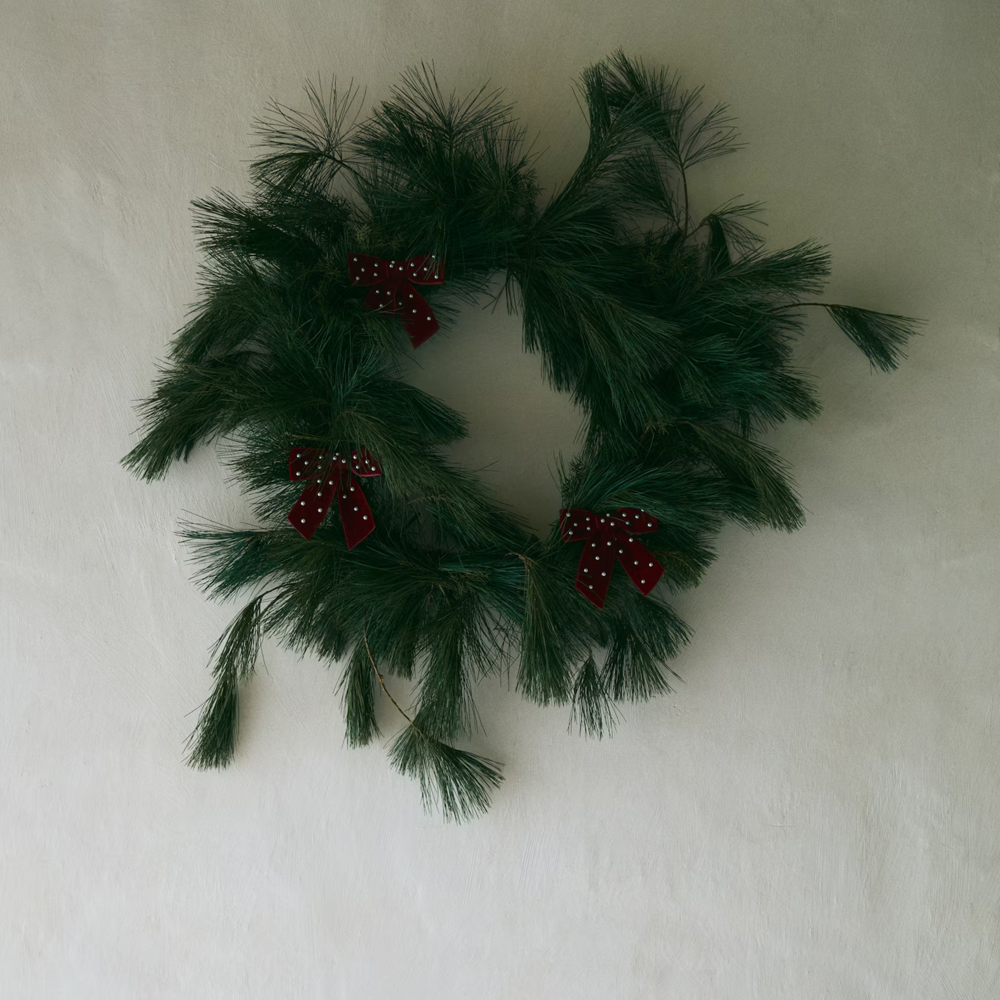 H&amp;amp;M Home&#039;s large beaded bow decorations on a Christmas wreath hung on a wall