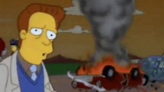 Troy McClure looking at the camera while a car burns behind him.