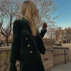 Helene wears a green velvet blazer with gold buttons.