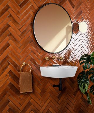 Ocher tiled bathroom with white basin and circular mirror by Walls and Floors