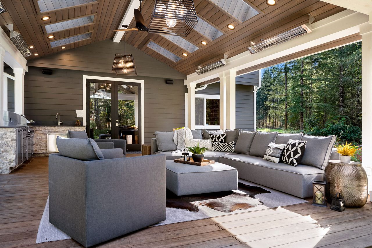 A living room with large grey sofas, a vaulted ceiling, and a cowhide rug