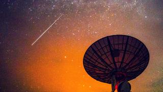 C-band satellite dish at night with a shooting star in the sky