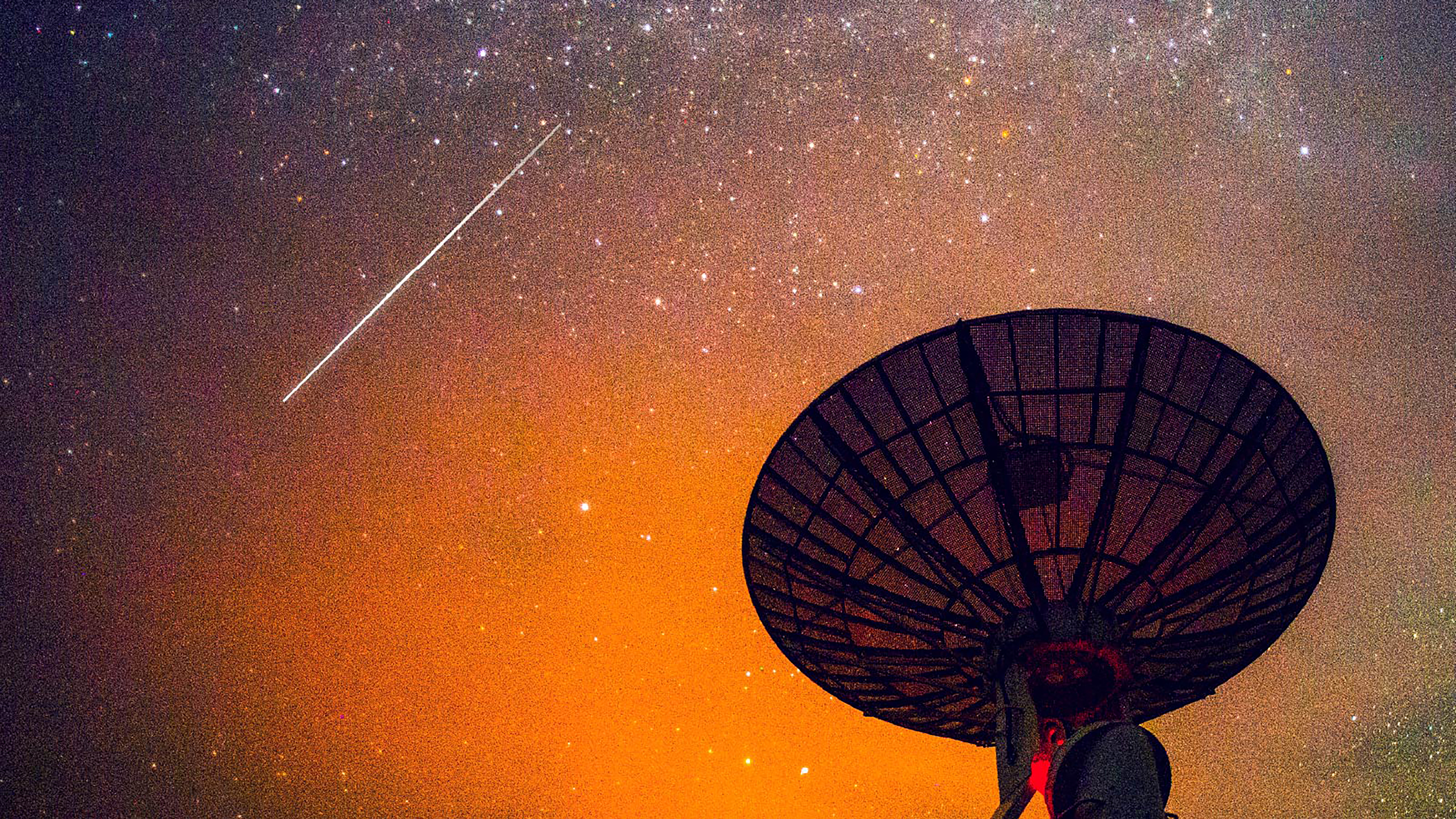 C-band satellite dish at night with a shooting star in the sky
