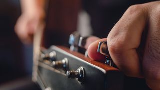 Close up of hands tuning an acoustic guitar