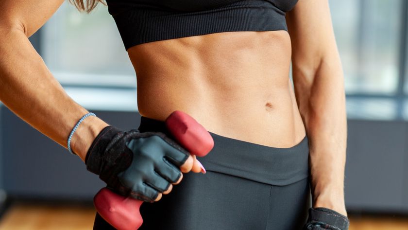 woman holding dumbbell with defined abs 