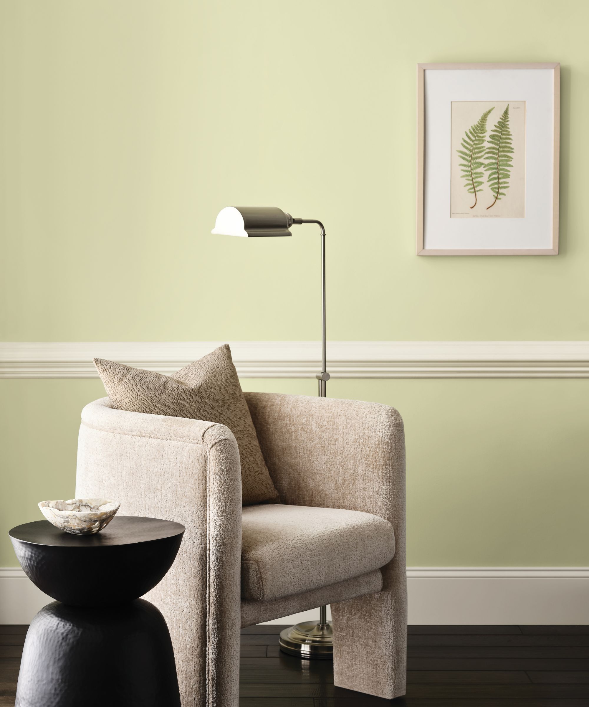 Living room with lime green walls, wall molding, linen armchair, and botanical print and floor lamp