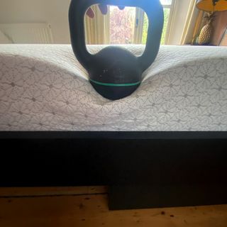 A kettlebell sitting on the edge of a mattress to measure edge support