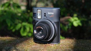 Fujifilm Instax Mini 41 camera on a mossy wall in front of green plants