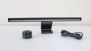 A monitor light bar along with its dial controller and USB-C cable