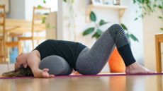Woman lies on the floor with a bolster underneath her midback