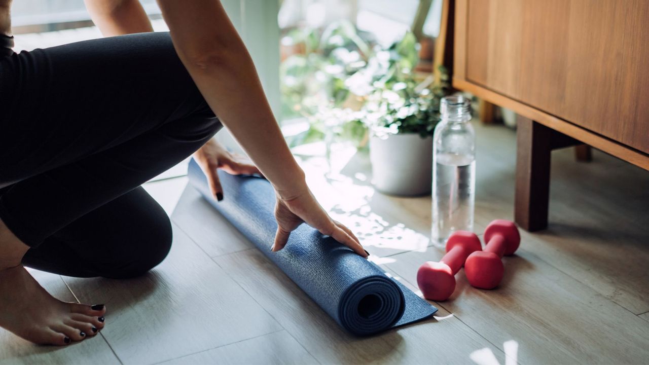 Strength training at home: A woman rolling out her workout mat